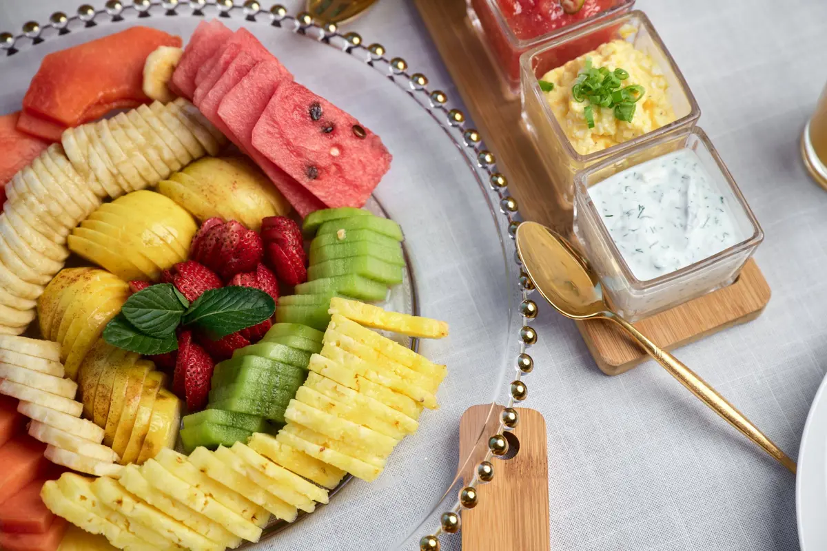 Breakfast served at an Aldea Kaan Tulum villa: papaya, watermelon, banana, kiwi, strawberries and pineapple beside cups of eggs and salsa