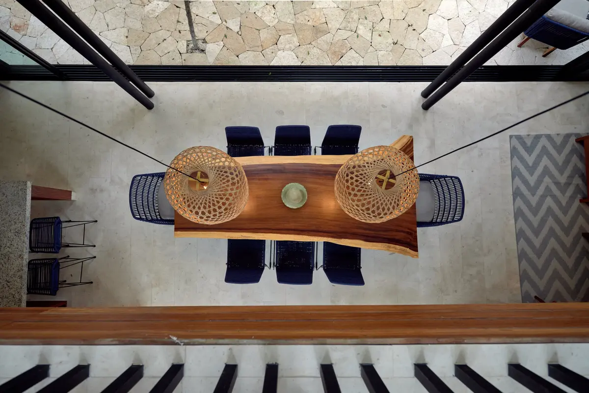 Casa David dining table with blue chairs and two woven pendant lamps seen from the floor above