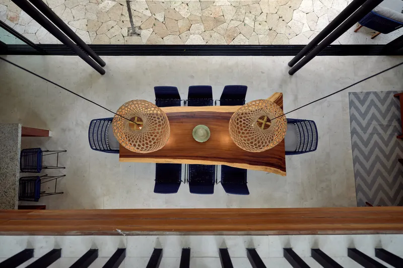 Casa David dining table with blue chairs and two woven pendant lamps seen from the floor above