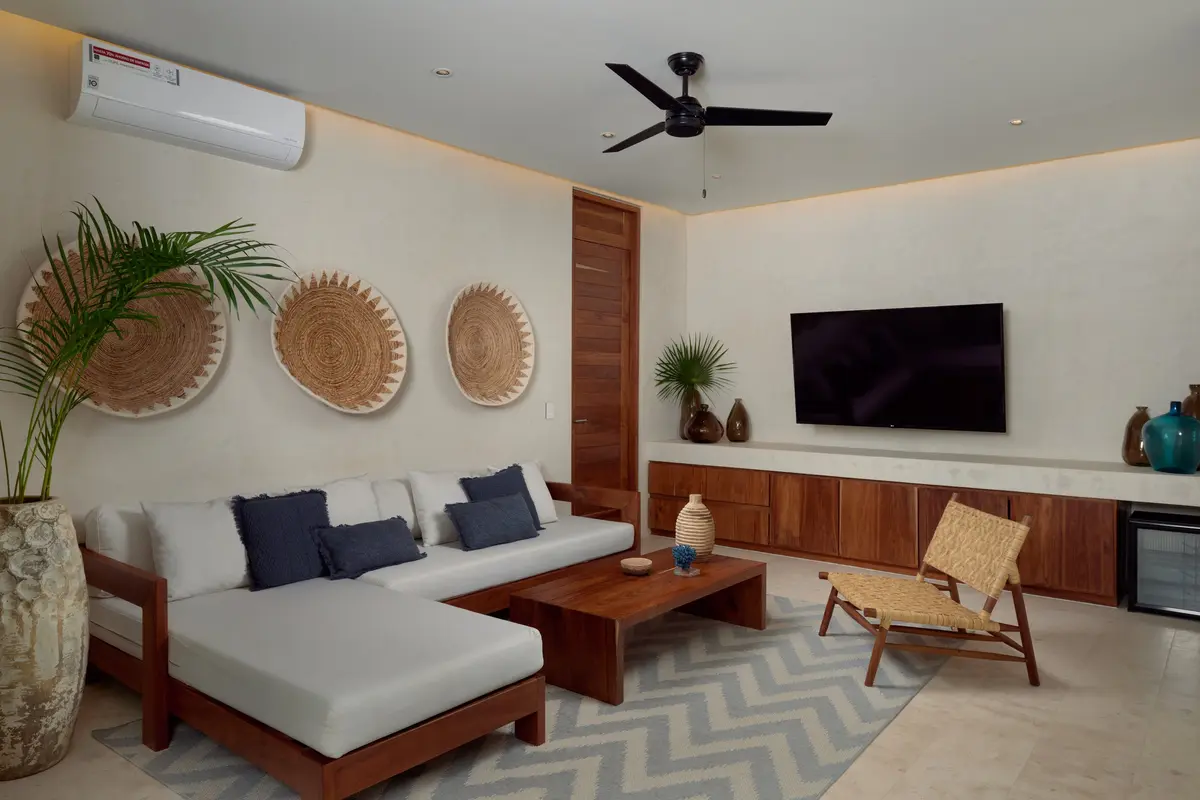 Casa David living room with an L shaped sofa, wooden coffee table, wall mounted TV and woven wall discs