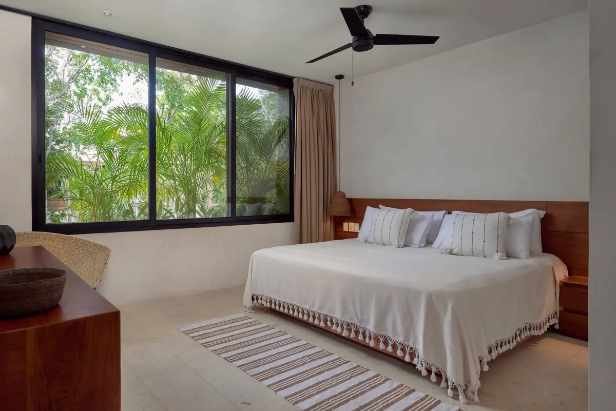 Casa David master bedroom with a king bed under a white tasselled coverlet, a ceiling fan and a wide window onto palms