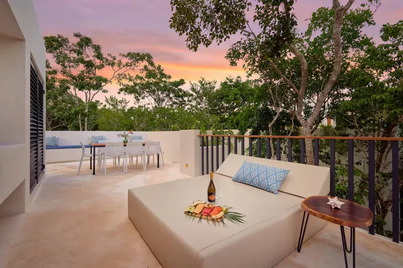 Casa David rooftop terrace at sunset with a daybed, a fruit platter and a dining table behind