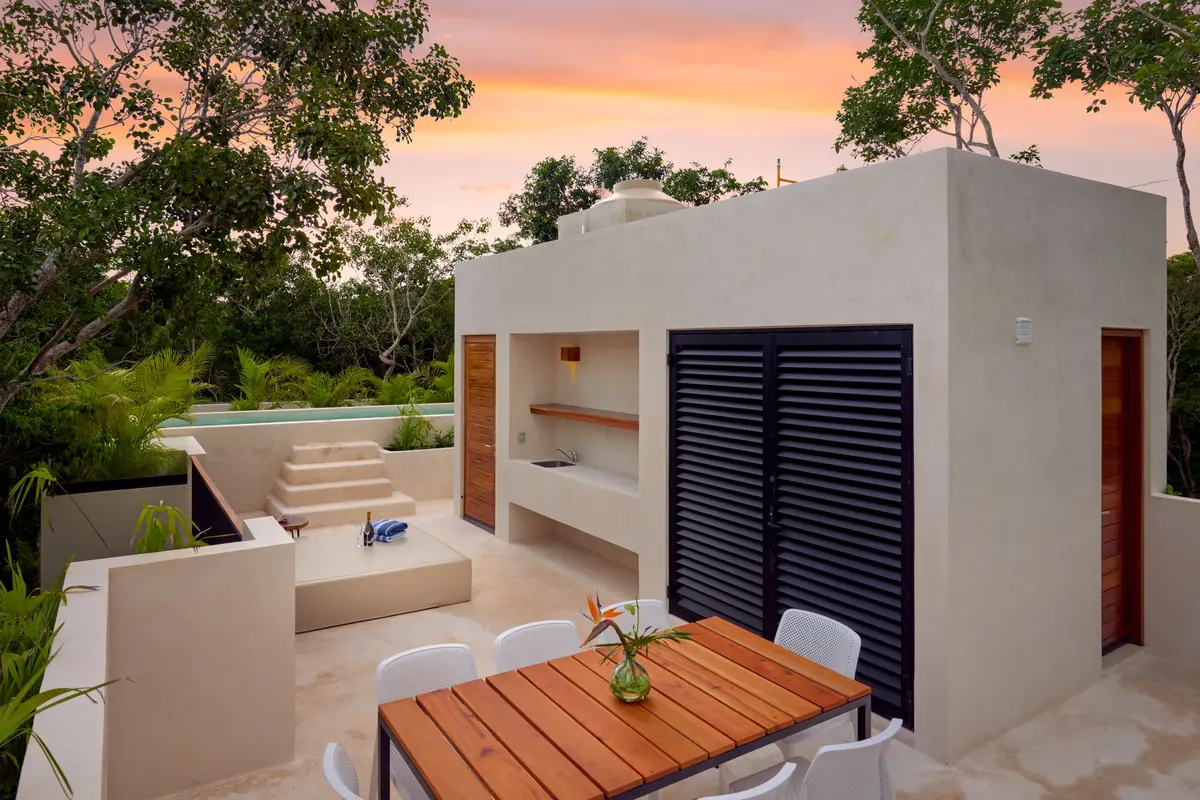 Casa David rooftop terrace at sunset with a wooden dining table, louvered doors and the pool