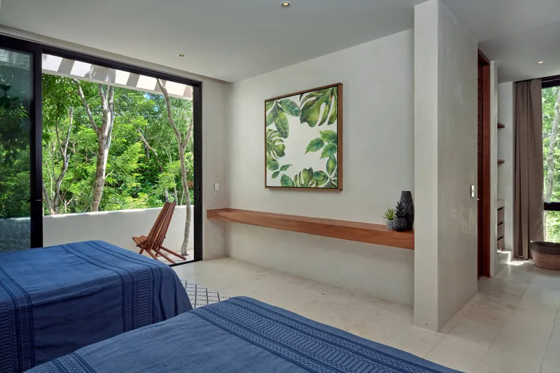 Casa Lucas guest bedroom with two queen beds, a framed leaf print and a sliding door open to a terrace with jungle views