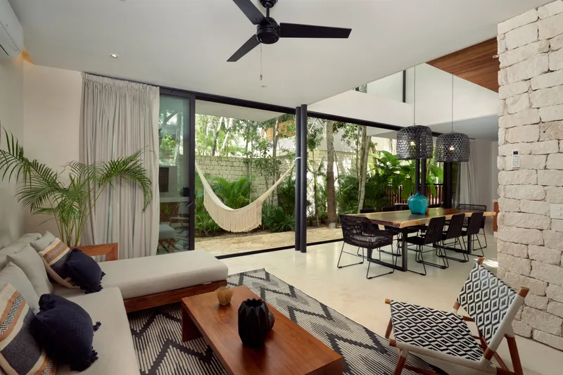 Casa Lucas living room with a white sofa, dining table and glass doors onto a garden with a hammock