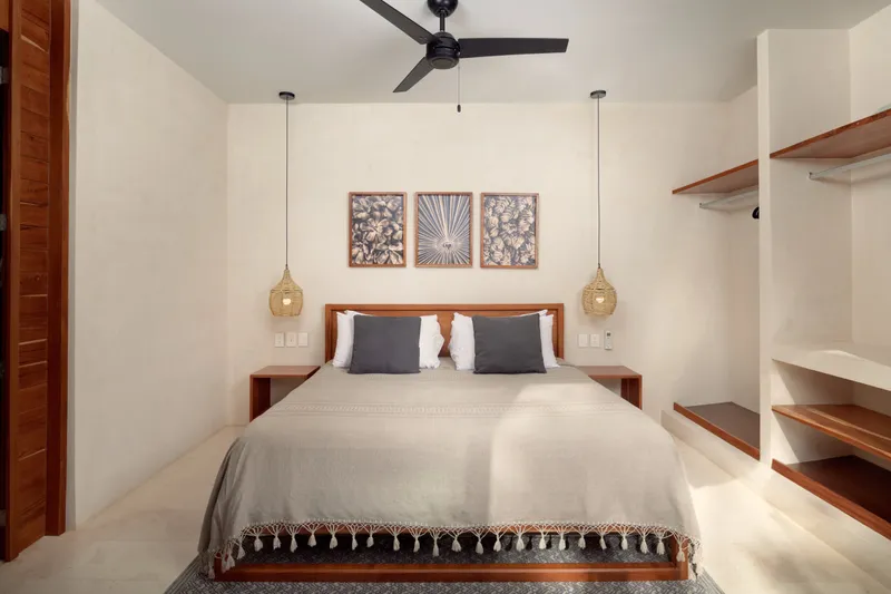 Casa Lydia bedroom with a wooden headboard, three framed prints and woven pendant lamps