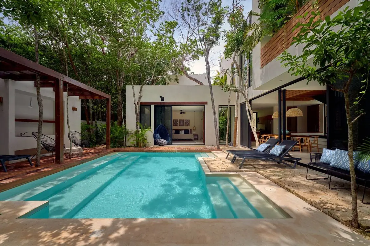 Casa Lydia pool by day with loungers, a covered lounge at left and the master bedroom opening onto the pool deck