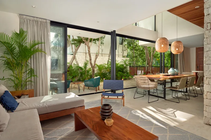 Casa Thomas living and dining area with a daybed sofa, wooden coffee table and glass walls onto the garden
