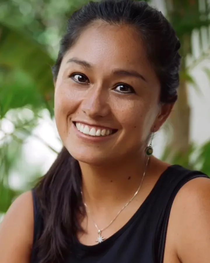 Gaby, concierge of Aldea Kaan Tulum, smiling in front of palm leaves